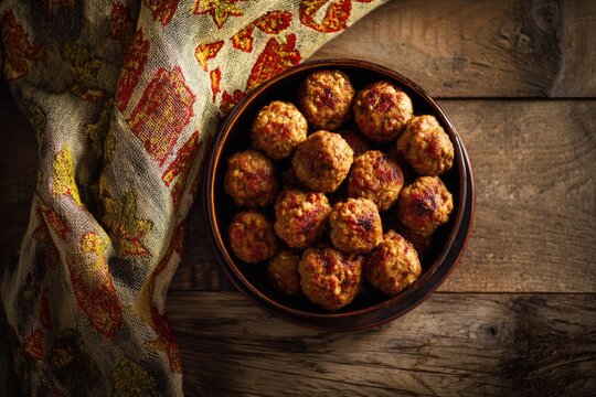 Plump, savory meatballs nestled in a rustic bowl on a wooden surface