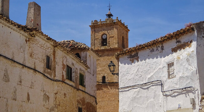 Scenic view of El Toboso town with the church bell tower rising above traditional white houses, Toledo, Spain. Authentic Mediterranean street and historical architecture in the homeland of Dulcinea.