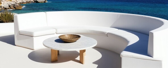 Obraz premium Modern white curved sofa and marble table on sunny terrace with ocean view. Outdoor lounge area offers tranquil relaxation and coastal escape with blue sea and rocky shore.