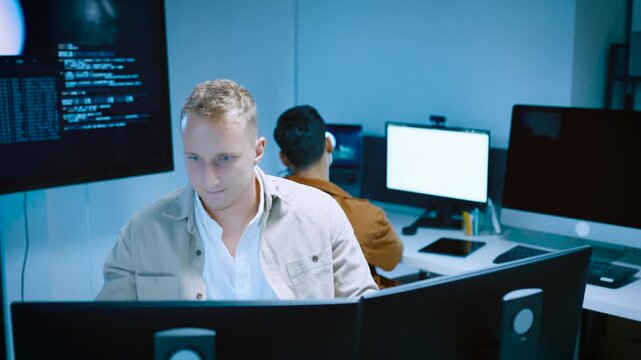 Smart young male programmer raised finger with an idea while working on computer screens in modern high tech laboratory office