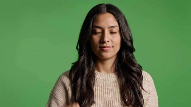 Woman demonstrates hand gestures for communication against a studio green screen background with subtle facial expressions