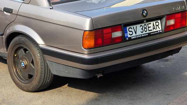 Piatra Neamt, Romania - June 7, 2025: Back exterior of a vintage beige BMW E30 318i with a Romanian license plate, a classic design, and a unique ATS Cup wheel.