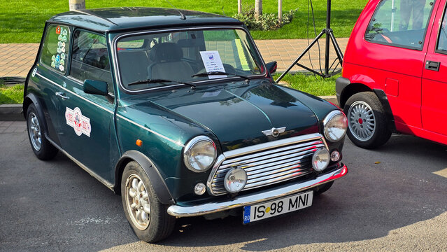 Piatra Neamt, Romania - June 7, 2025: View of a dark green 1989 Mini Cooper, showcasing its classic design, chrome grille, round headlights, and white stripe.