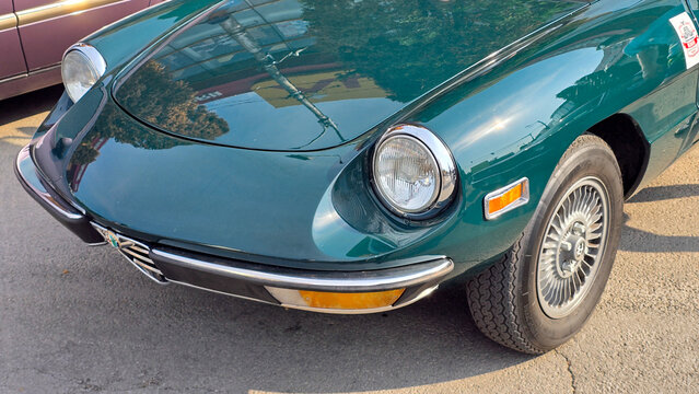 Piatra Neamt, Romania - June 7, 2025: Close-up of a 1976 green Alfa Romeo Spider front quarter, highlighting its classic headlight, turn signal, chrome bumper, and distinctive alloy wheel.