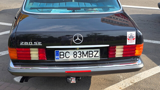 Piatra Neamt, Romania - June 7, 2025: Rear view of a black classic Mercedes-Benz 280 SE, highlighting its iconic taillights and chrome bumper. The car is parked outdoors on asphalt.