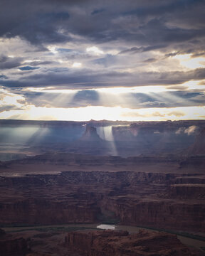 Sunbeams breaking through clouds over a desert canyon