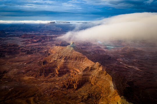 Dramatic clouds roll over a vast red rock canyon landscape