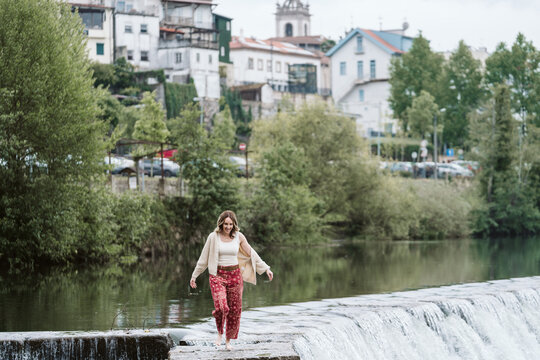 Carefree woman walking barefoot on a river weir