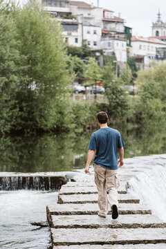 Man walking across stone steps over a river