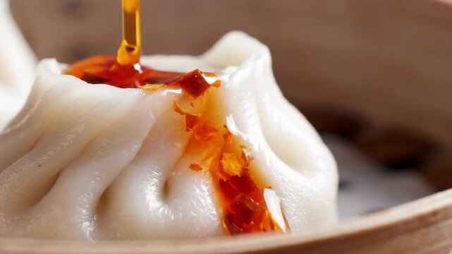 Pouring chili oil onto a steaming dim sum dumpling
