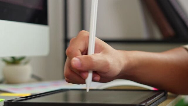 Close up of creative graphic designer drawing on digital screen tablet with precision stylus pen