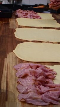 Vertical view putting ham on dough assembling the pan de jamon breads
