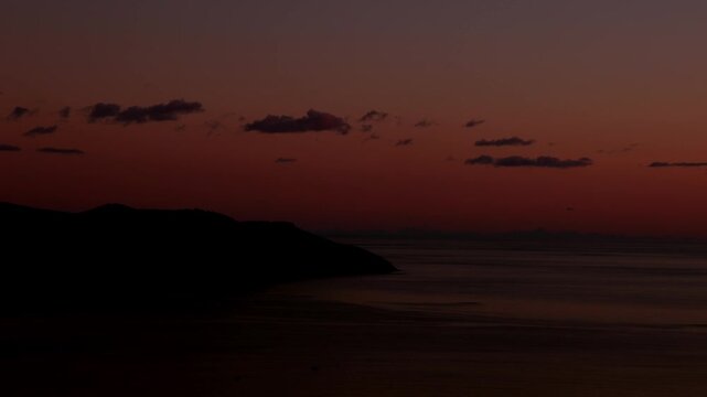 Sunset Time Lapse Over Calm Sea. Timelapse of a calm sea at sunset with coastal hills, pastel sky and pink clouds. Peaceful evening seascape with soft natural light.