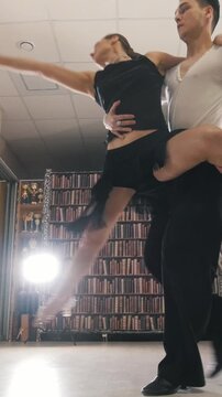 Young attractive man and woman dancing Latin American dance in costumes in the Studio, focus on feet, view from the bottom up