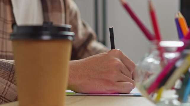 Designer drafting fresh concept layout using black felt-tip pen on sketchbook in studio setup