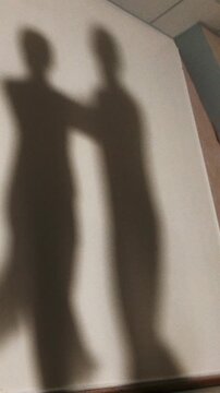 Shadow of man and woman dancing and rehearsing Latin American dance in costumes