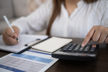 Fototapeta premium Woman calculating household expenses with a calculator and bills at home, representing personal finance, budgeting, and money management.
