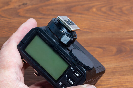 Holding a camera flash trigger in hand.