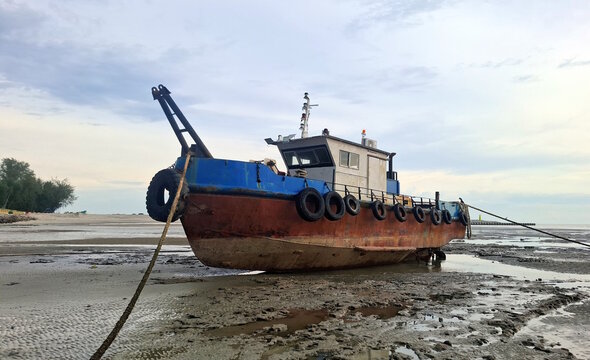 Stranded fishing boat at the beach during sunset