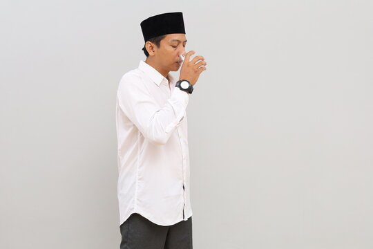 Asian Muslim man drinking a glass of water to break his fast, Ramadan concept.