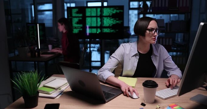 Serious businesswoman in formal clothing types important document on computer. Focused woman in glasses prepares detailed report working in office