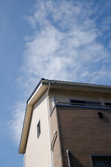 Obraz premium 青空の背景に2階建ての住宅の外壁が色褪せている。外壁の劣化、色褪せや汚れ
