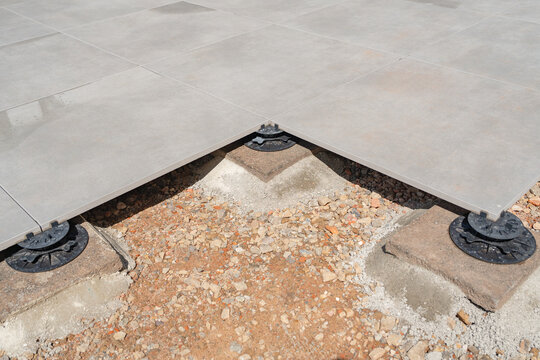 Corner joint of raised floor tiles on plastic pedestal. Top view of adjustable terrace paving support system