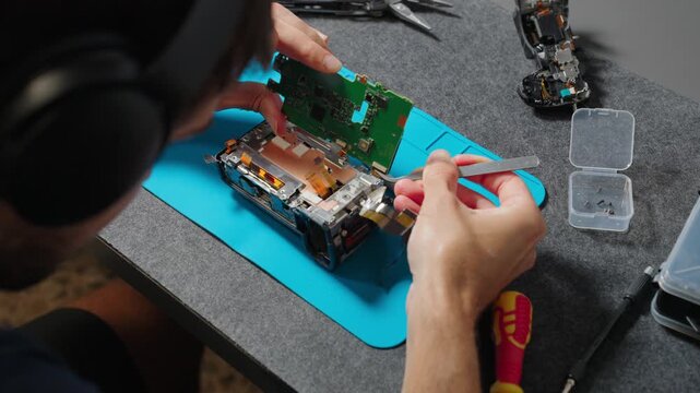 Technician hands carefully repairing a professional digital camera circuit board, focusing on electronics maintenance and service.