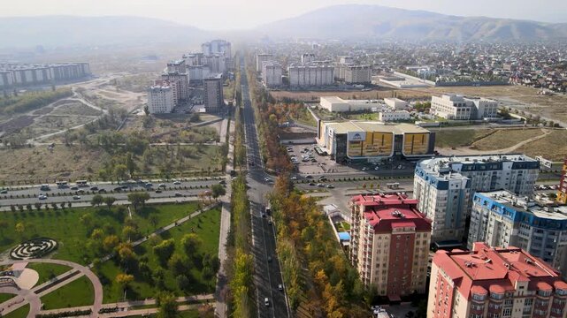 Drone flyover along an urban avenue in Bishkek, Kyrgyzstan, passing commercial buildings near Ala Archa shopping center.
