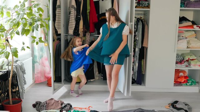 Playful preteen dancing wildly wearing large clothes alongside young kid.