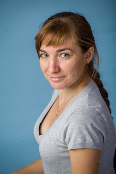 Young woman smiling while sitting against blue background  