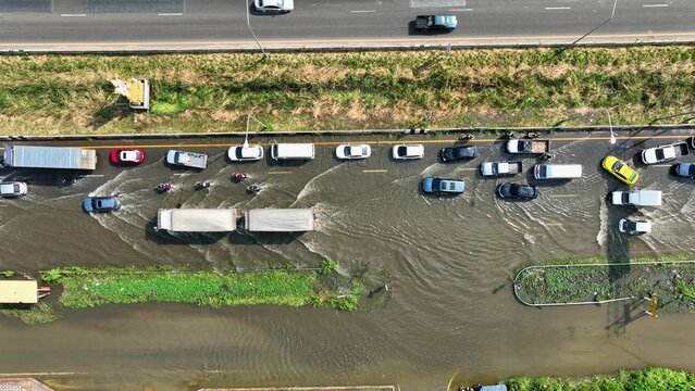 An aerial drone shot shows deep floodwaters stalling traffic, revealing gaps in drainage systems, climate adaptation, disaster response, infrastructure durability, and long-term urban resilience.
