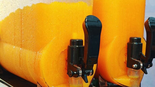 Close-up of slushy machines with orange flavors.