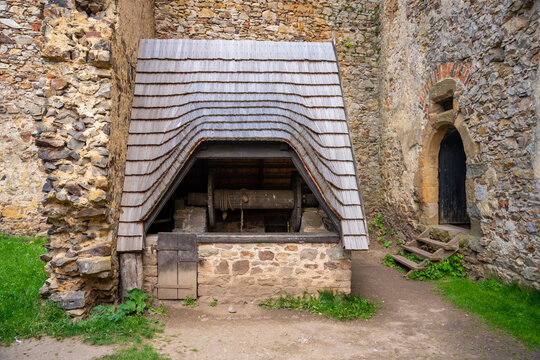 Historic stone well with wooden roof structure inside Tocnik Castle courtyard in Czech Republic. Medieval engineering and water supply concept