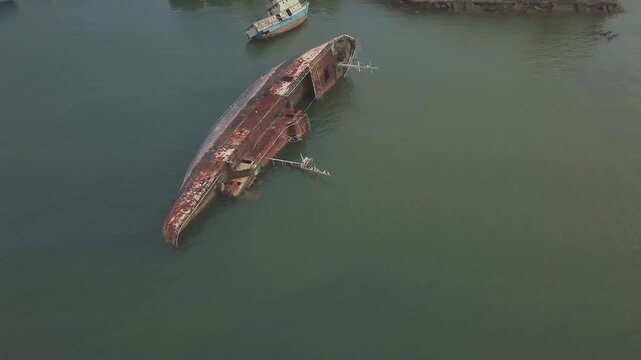 Aerial View of a Large Rusty Shipwreck Capsized in Shallow Sea Water