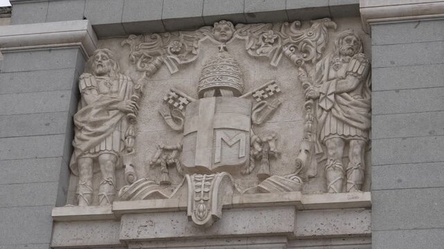 Stone relief on the Royal Palace of Madrid, Community of Madrid, Spain, depicting papal insignia, heraldic emblems and sculpted saints within the eighteenth century Baroque palace complex, pan