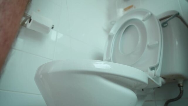 Man urinating toilet bathroom interior. Close up male body near toilet seat during restroom use. Personal hygiene, sanitation, domestic bathroom facilities