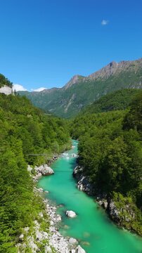 Turquoise Water Of Soca River Flowing Through Dense Green Forest And Mountain. - aerial vertical shot