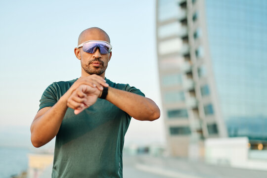 Portrait opf a young man prepering to exercise and run and looking at watch in sportwear posing for a portrait outdoors