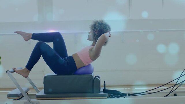 Woman bracing on Pilates reformer, curling torso, leg cycles, toning abs with purple-pad, flares