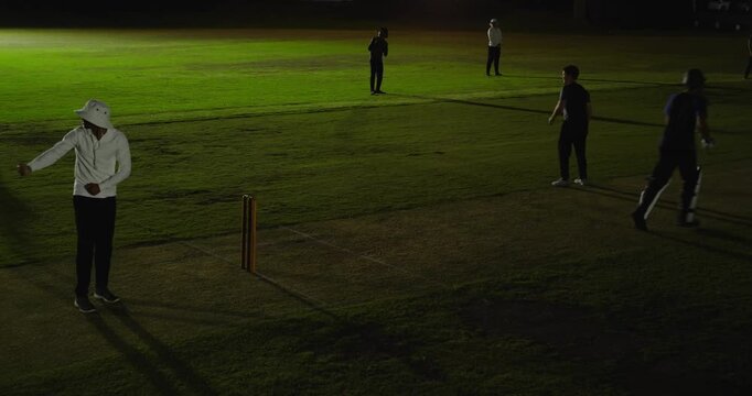 Wicketkeeper collecting missed ball whipping off bail and appealing, floodlights, copy space