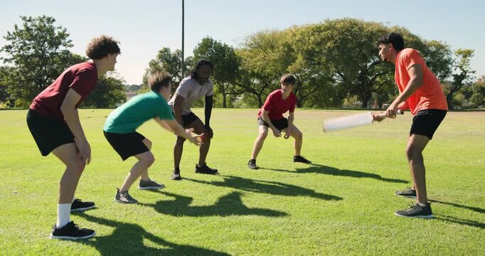 After batsman tapping ball, diverse male team fielding red cricket ball on field sharpening skills