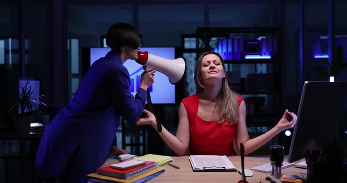 Angry manager screams near meditating woman employee by megaphone in semi-dark office. Female boss puts pressure on worker at deadline in workplace