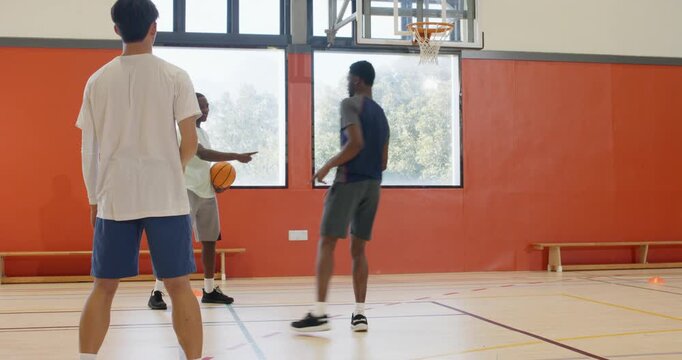 Receiving bounce pass from teammate, african american male dunking on court during practice