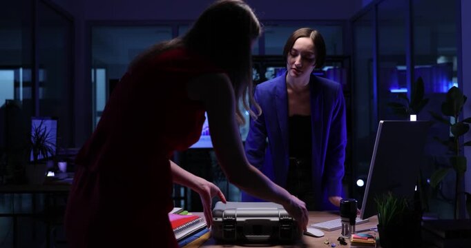 Partner puts briefcase of cash money to businesswoman in dark office. Female entrepreneurs get large financial income from sales at commercial company
