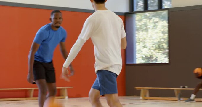 Grabbing loose basketball on court after bounce, man dribbling past defender to score