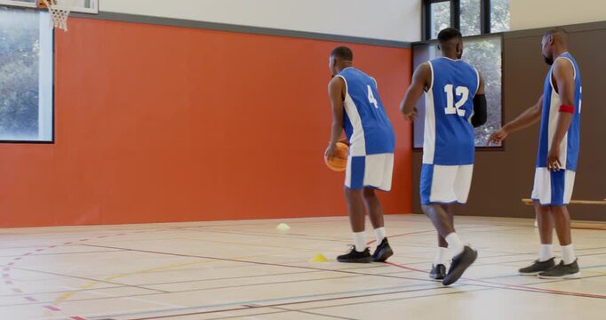 Clapping, african american friends dribbling ball past cones at gym shooting hoops, copy space