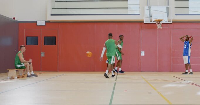 Closing defender urging male player dribbling leaping toward hoop on court scoring