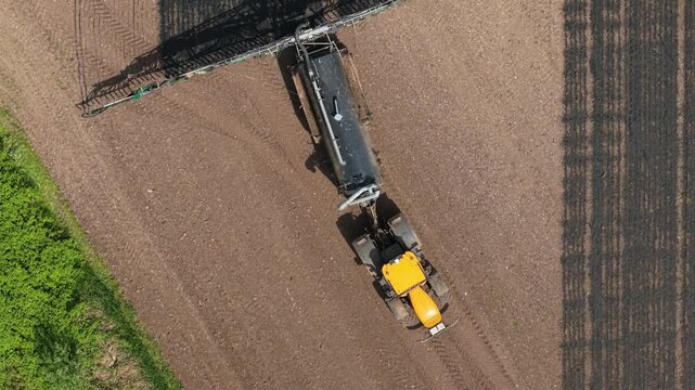 Organic fertilizer application tractor turning in agricultural field. Liquid manure nutrient spreading supporting soil fertility, crop productivity, precision farming efficiency. Modern farm machinery