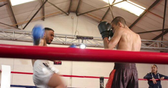 Landing kick male boxer knocking opponent down and celebrating with female coach in boxing ring